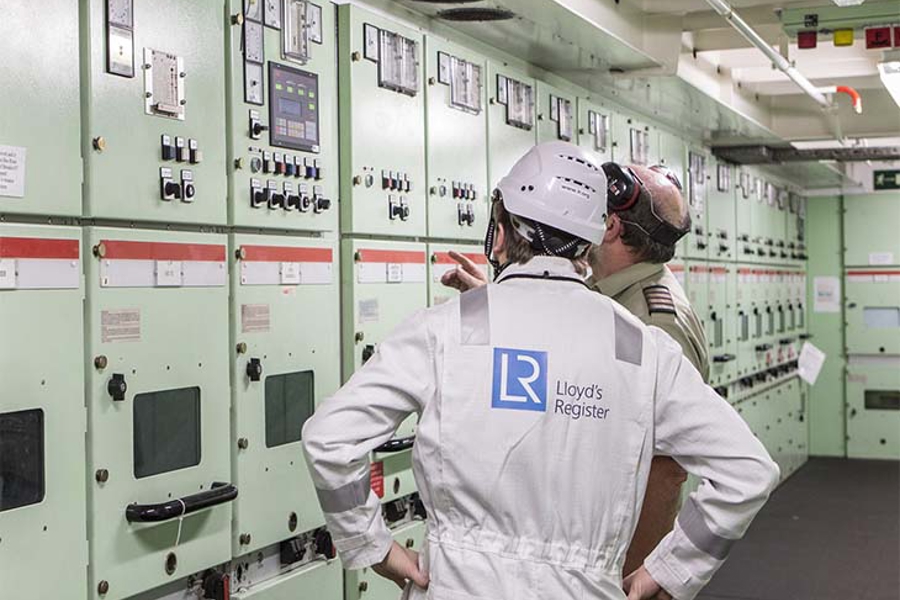 Two workers in boiler suits in the electric controls room.