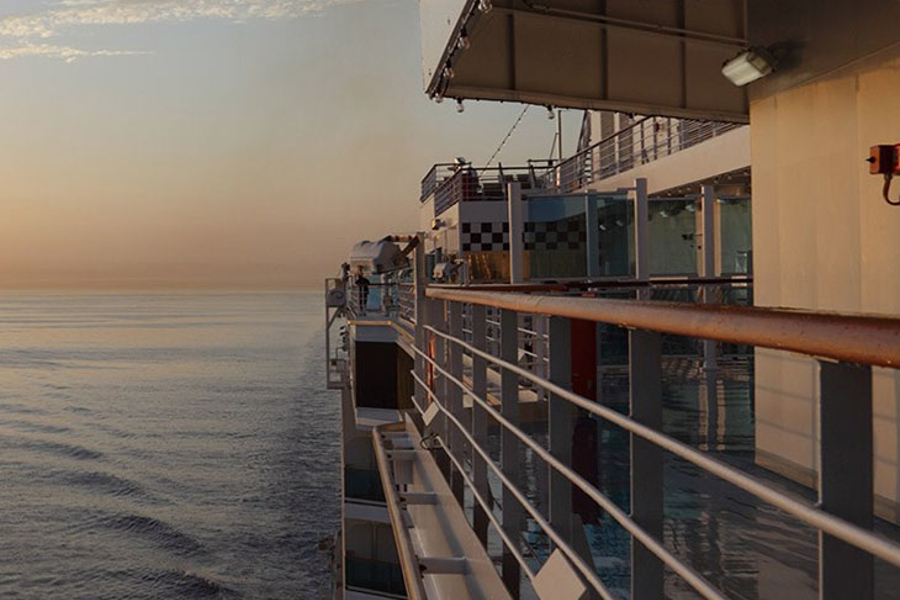 View of the ocean from the side of a passenger ship at sunset.
