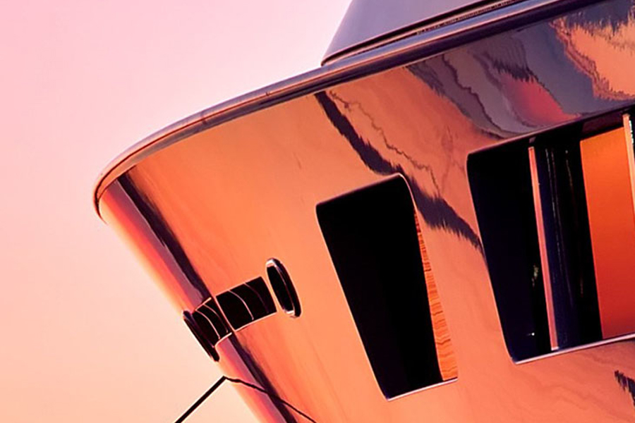 The bow of a yacht coloured by pink and gold sunset light.